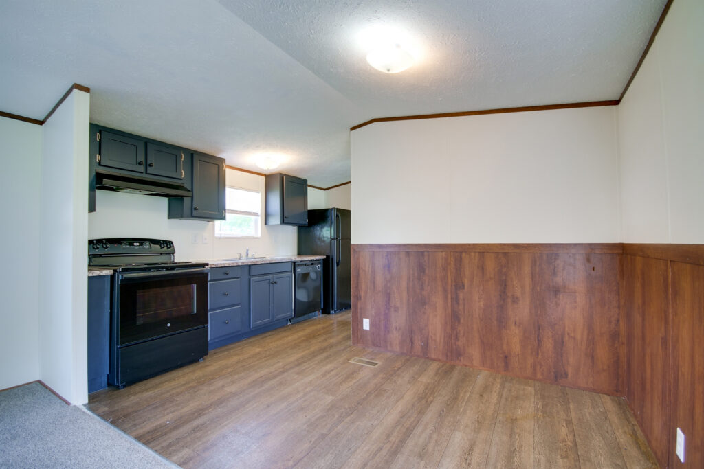 an empty kitchen with wood floors and black appliances